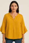 Mustard Ruffle Sleeve Blouse  This loose-fitting mustard blouse features a soft texture, a notched neckline, and stylish ruffled sleeves. Lightweight and flowy, it’s perfect for a casual day out or dressed up with jeans or trouser