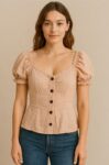 This blush pink puff-sleeve top features a sweetheart neckline, ruched elastic detailing, and a row of bold front buttons