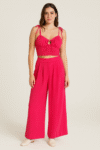 A vibrant three-piece pink set featuring wide-leg pants, a smocked crop top with tie straps,